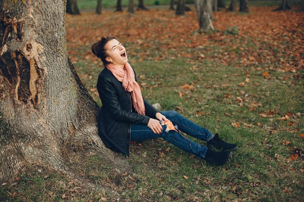 Woman with a leg injury. The wounded girl sitting by the tree. The wound is bleeding.