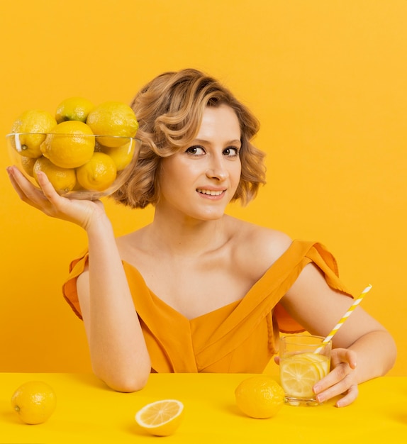 Woman with lemonade and holding bowl s with lemons