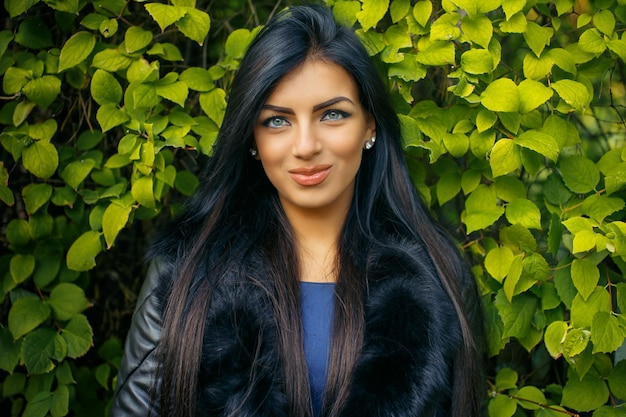 Woman with long black hair over green wall from leafes.