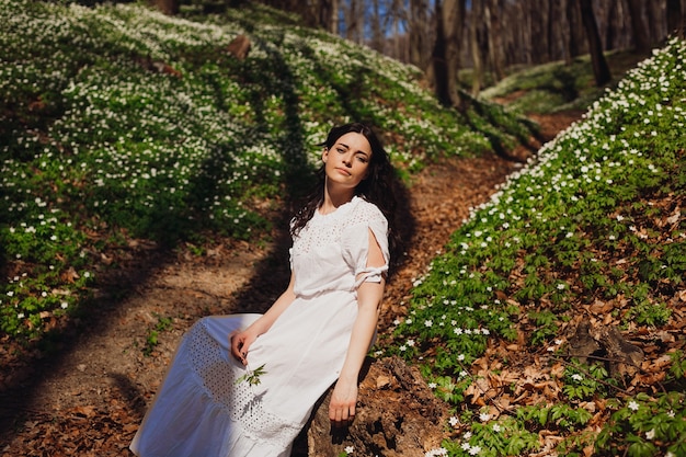 Woman with long dark hair sits on the ground 