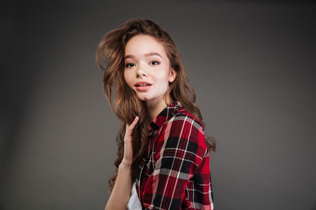 Woman with long hair in plaid shirt standing and posing