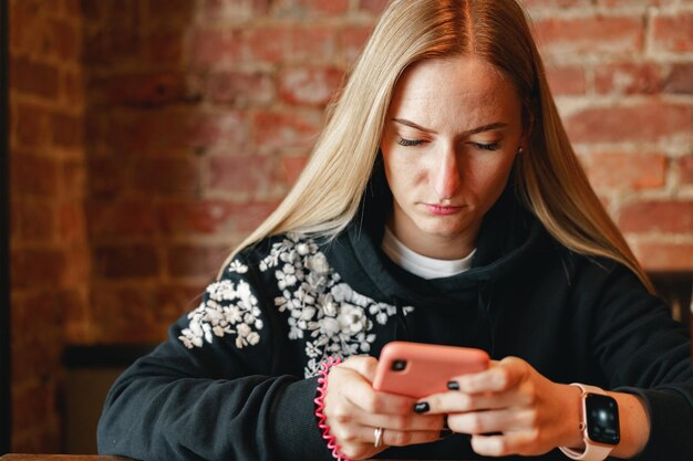 カフェのテーブルに座ってスマートフォンを使用して長い髪の女性