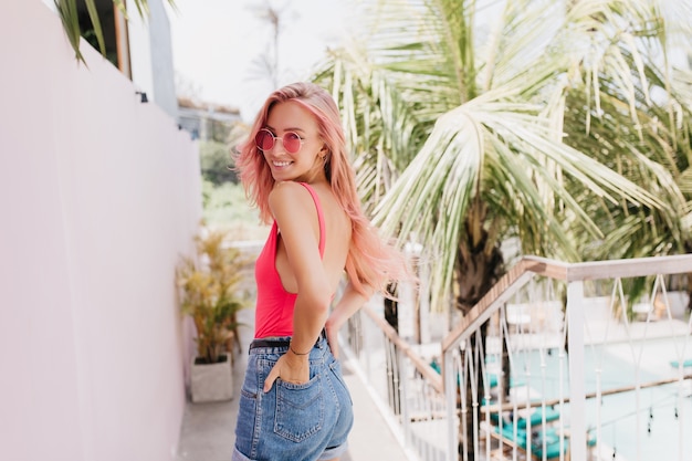Free photo woman with long pink hair posing in sunglasses on nature