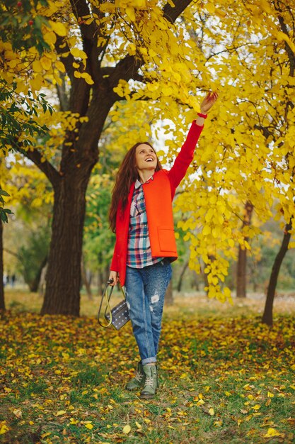 женщина с длинными волнистыми волосами, наслаждаясь осень в парке.
