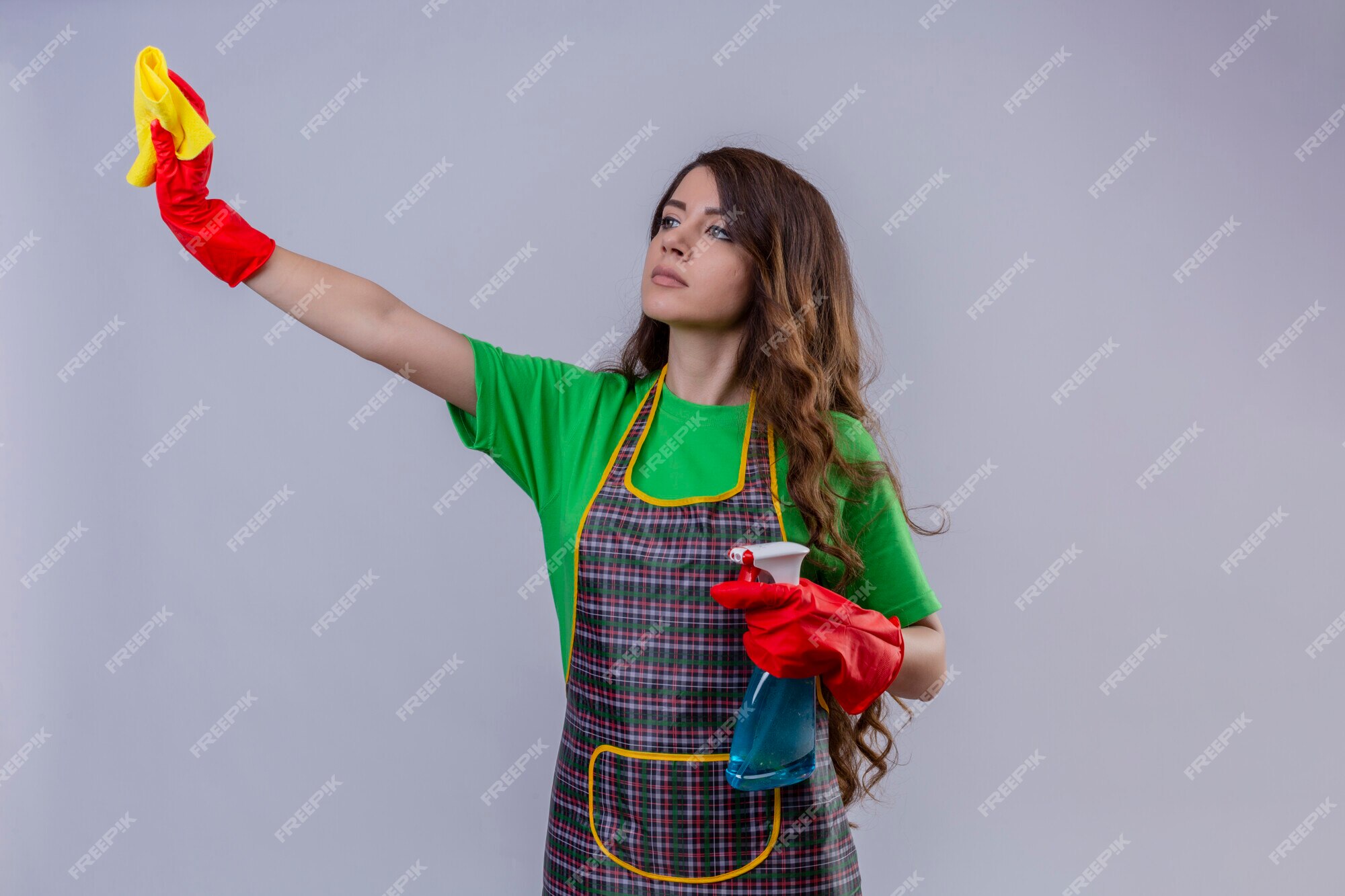 Free Photo | Woman with long wavy hair wearing apron and rubber gloves holding rug and cleaning spray looking aside with serious confident expression standing Free Photo | Woman with long wavy hair wearing apron and rubber gloves holding rug and cleaning spray looking aside with serious confident expression standing