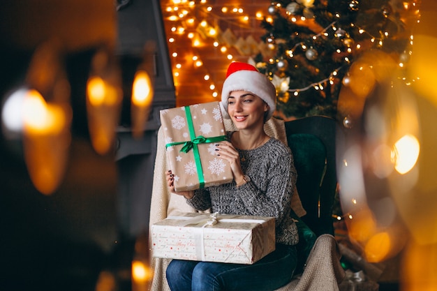 Woman with lots of presents by Christmas tree