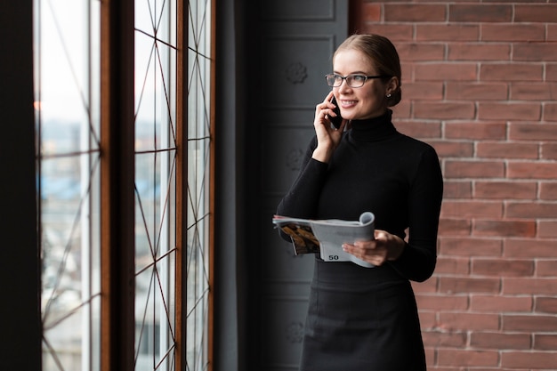 Foto gratuita donna con la rivista che parla al telefono