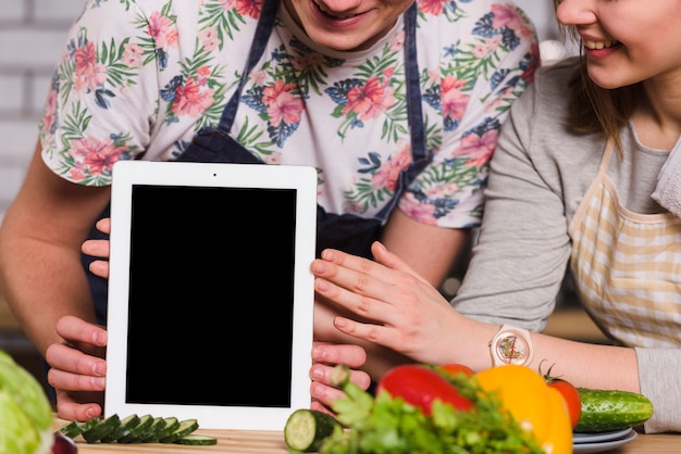 Woman with man holding tablet on kitchen table