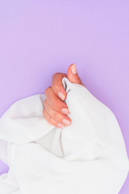 Woman with manicure done holding a white cloth with copy space