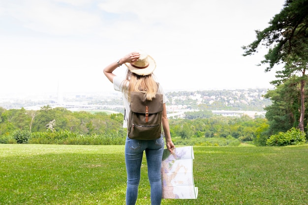 Woman with map is holding her hat