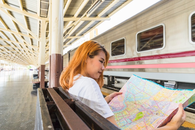 Donna con la mappa sul sedile vicino al treno sulla piattaforma