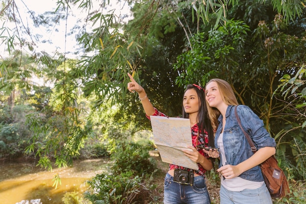 女性、森の中で彼女の女性の友人に位置を示す地図