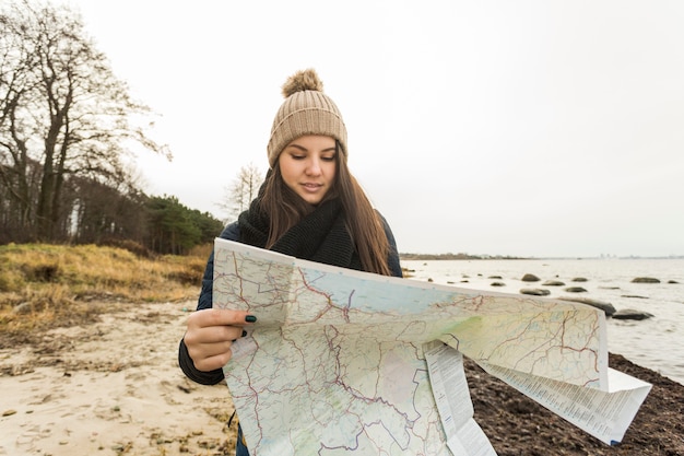 Foto gratuita donna con mappa camminando sulla riva