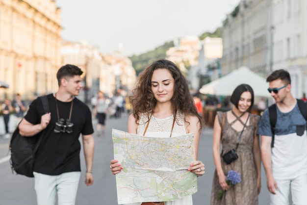 Woman with map walking with friends on street