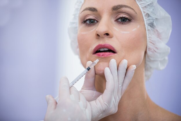 Woman with marked face receiving botox injection