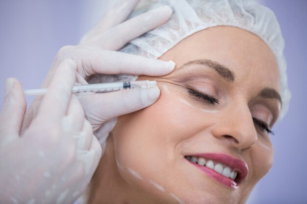 Woman with marked face receiving botox injection