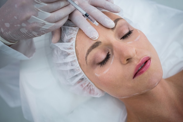 Woman with marked face receiving botox injection