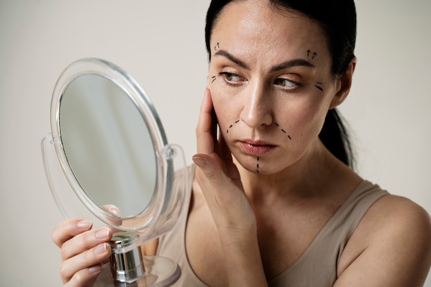 Woman with marker traces on face looking in the mirror