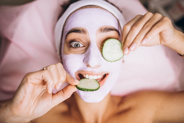 Woman with mask and cucumber on her eyes