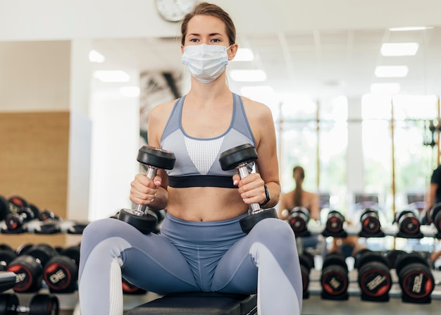 Donna con maschera che si esercita in palestra durante la pandemia