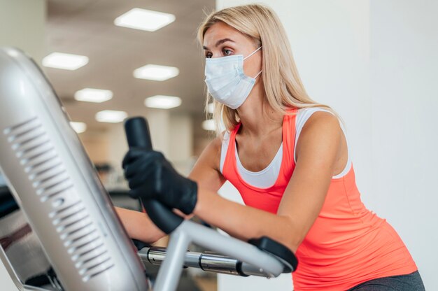 ジムで運動しているマスクと手袋を持つ女性