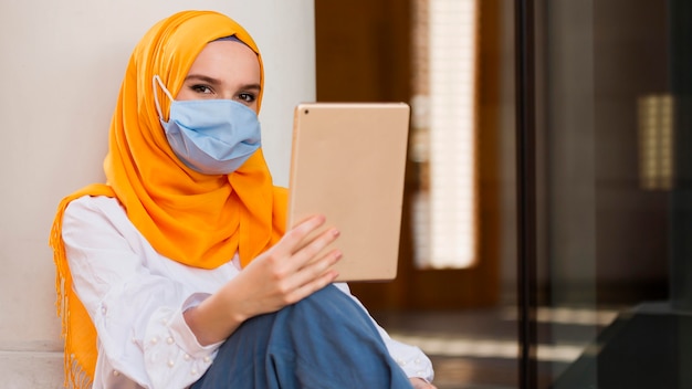 Woman with mask holding tablet