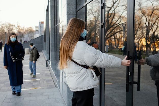 Free photo woman with mask opening door