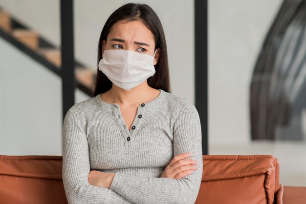 Woman with mask sitting on couch