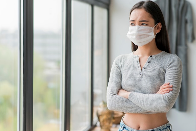 Free photo woman with mask standing with arms crossed