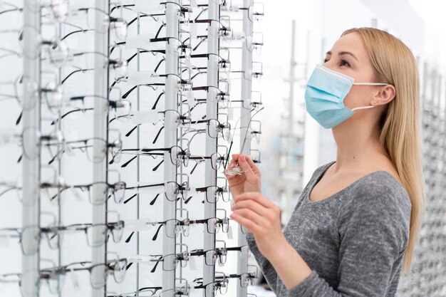 Woman with mask in store trying on glasses