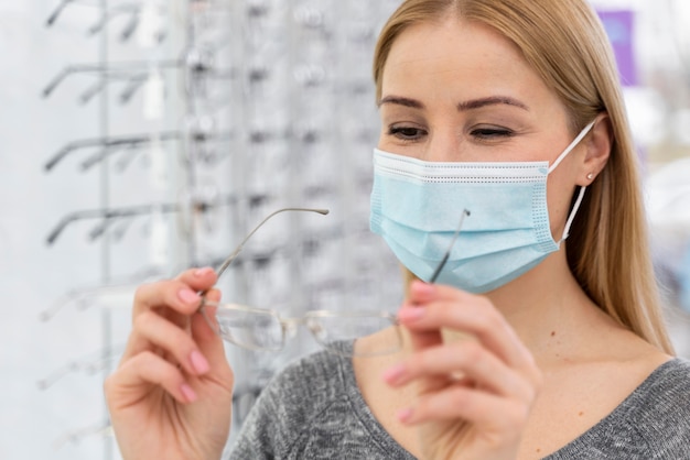 Donna con la maschera in negozio cercando su occhiali