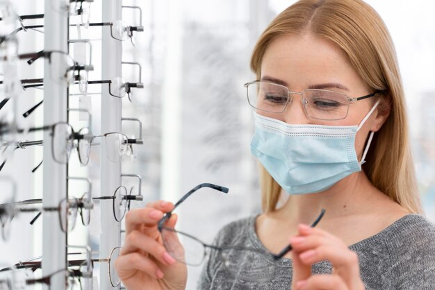 Woman with mask in store trying on glasses