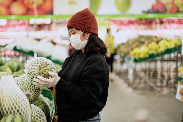 Женщина в медицинской маске покупает свежие продукты во время пандемии коронавируса