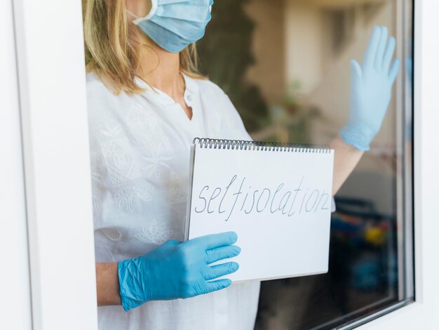 Woman with medical mask and gloves holding stay home notebook