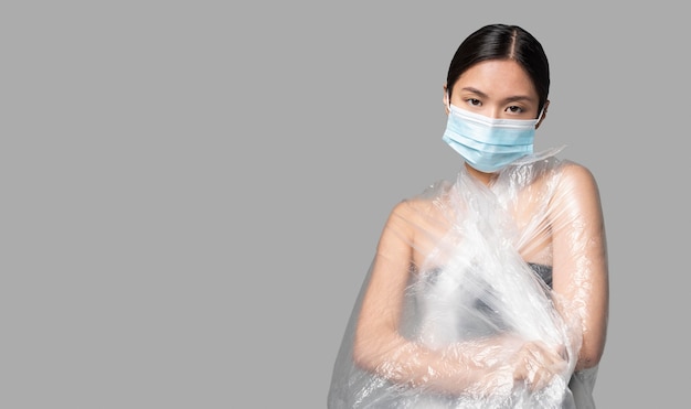 Foto gratuita donna con mascherina medica avendo il suo corpo ricoperto di plastica con copia spazio