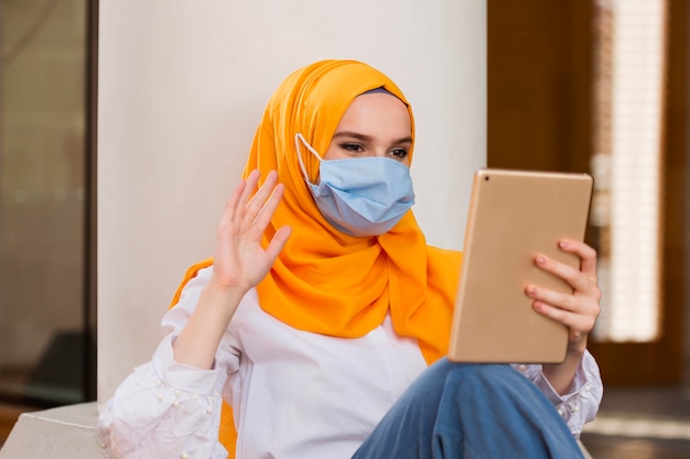 Woman with medical mask holding tablet