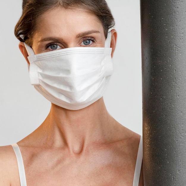 Woman with medical mask holding yoga mat