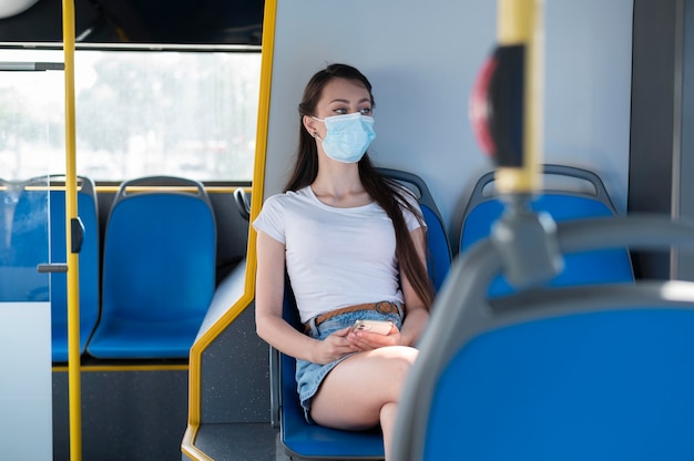Женщина с медицинской маской, использующая общественный автобус для транспортировки