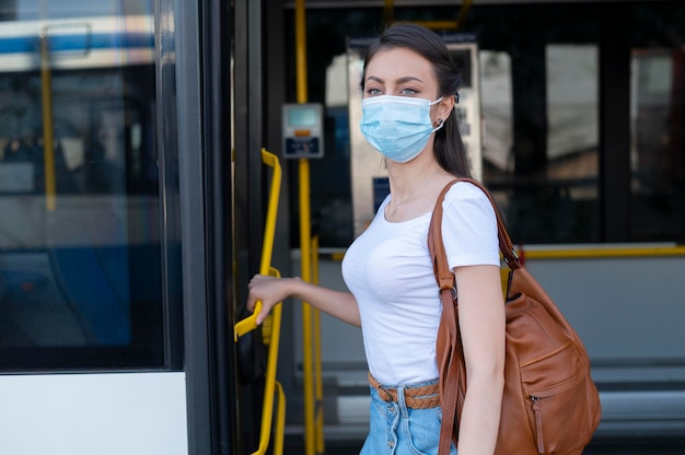 交通機関に公共バスを使用している医療マスクを持つ女性