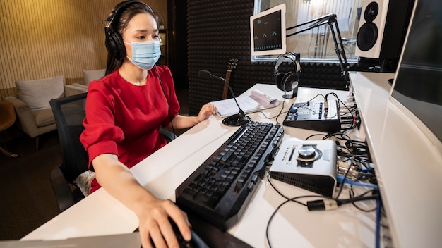 Woman with medical mask working at radio with professional equipment