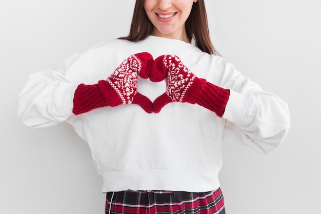 Woman with mittens making heart sign