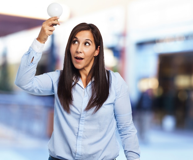 Woman with open mouth and holding a light bulb