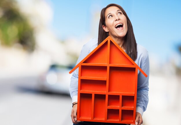 Woman with open mouth holding a red house