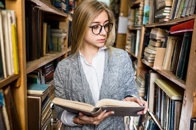 Woman with opened book looking at shelves