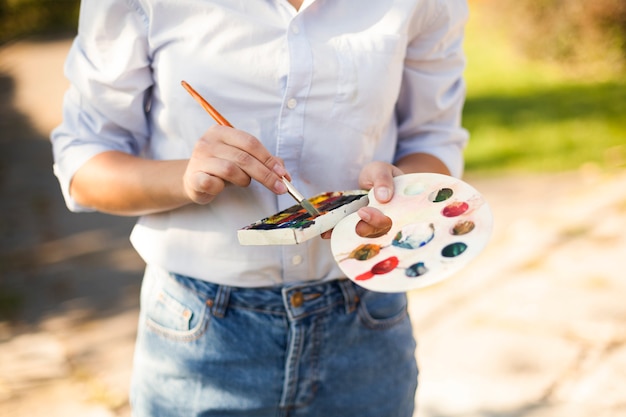 Free photo woman with paint brush and color palette outdoors