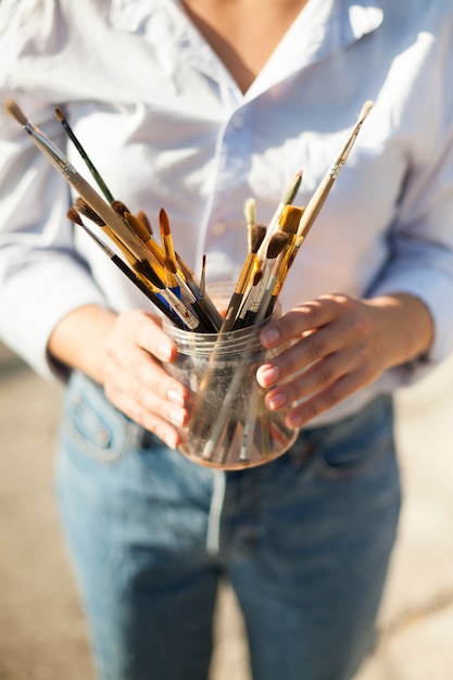 Woman with paint brushes outdoors