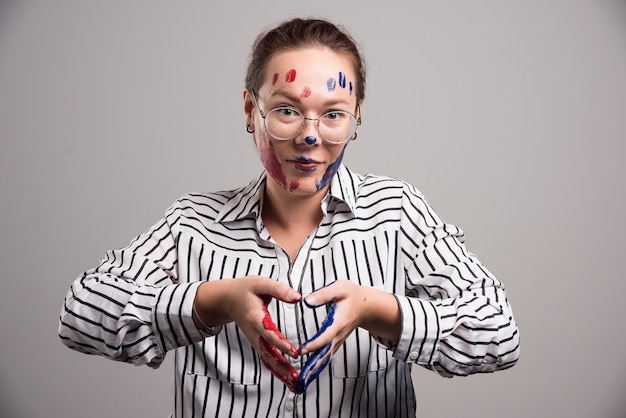 Free photo woman with paints on her face and glasses on gray background