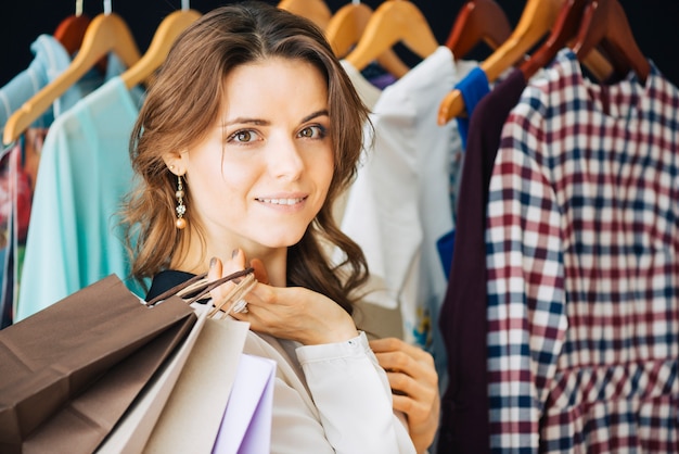 woman with paper bags near clothes rail
