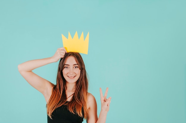 Бесплатное фото Женщина с бумажной короной, жестом мир