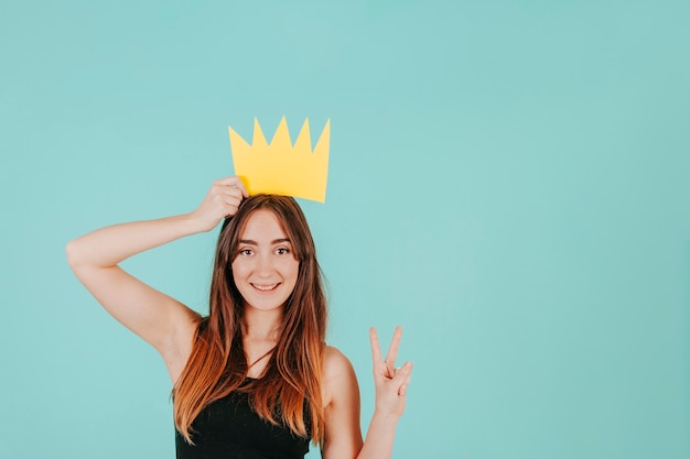 Foto gratuita donna con la corona di carta che gesturing pace